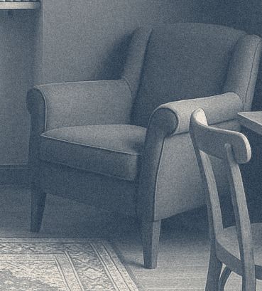 A green upholstered armchair beside a wooden chair