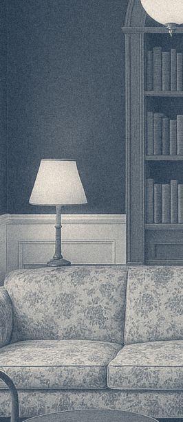 A table lamp beside a bookcase and a floral sofa