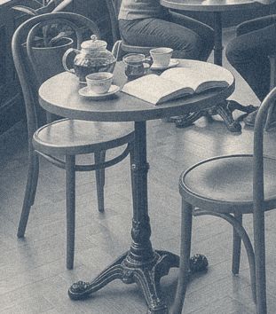 A small round table with a teapot, cups and an open book