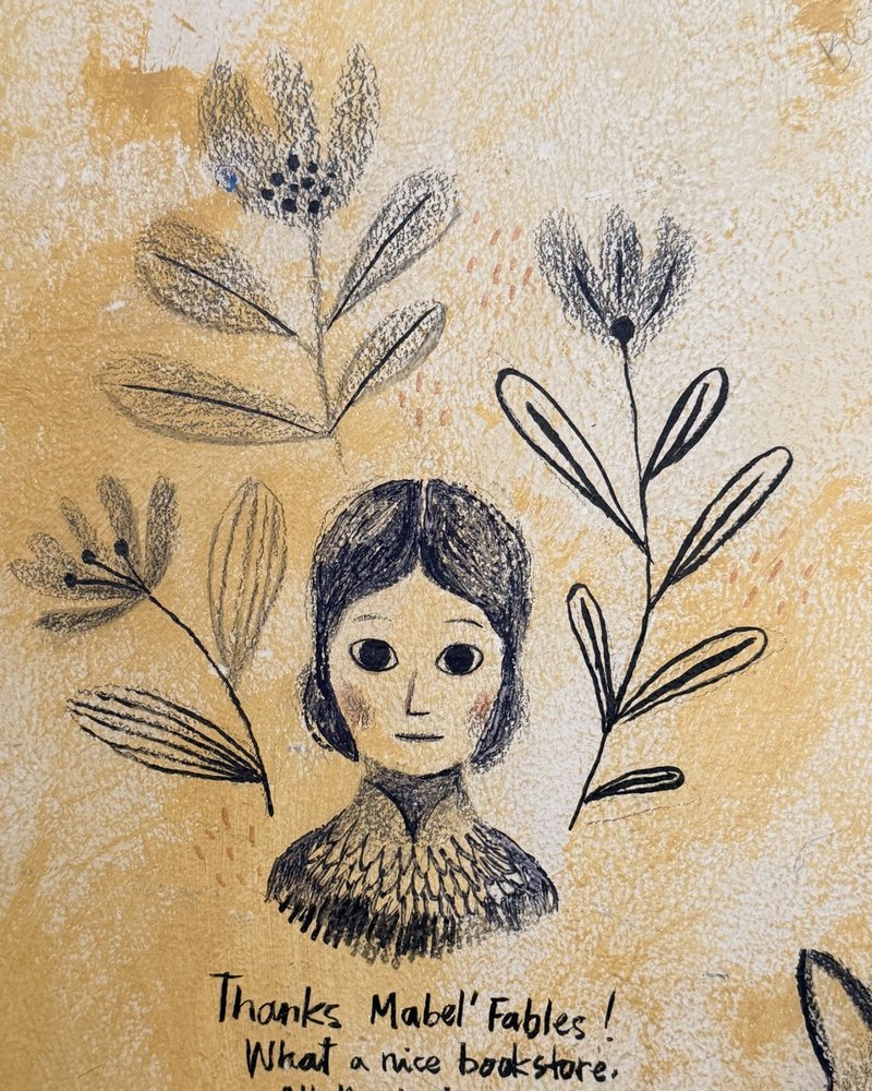 A portrait framed by leaves, drawn in ink and pencil on a yellow wall
